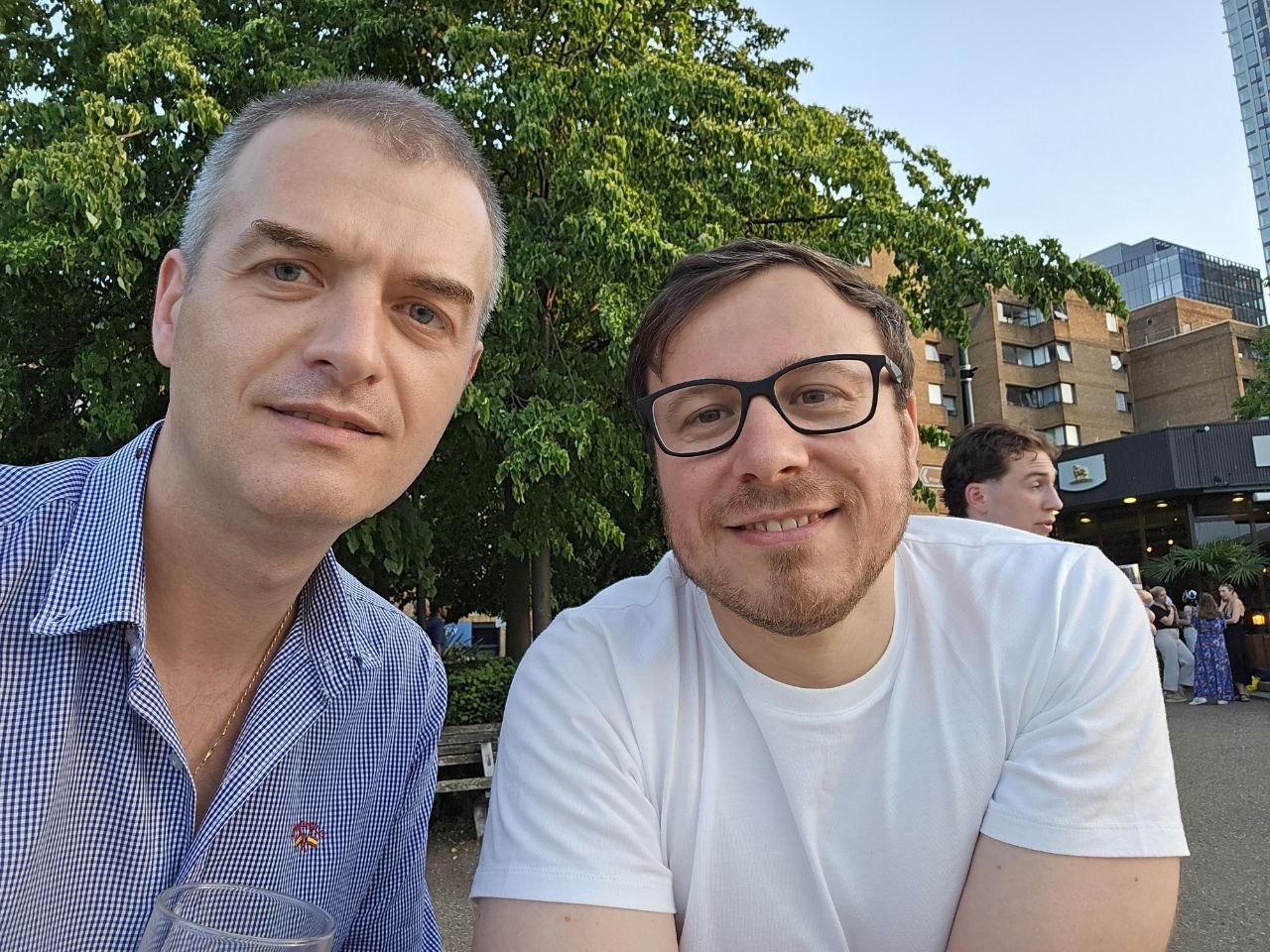 Two friends smiling together outdoors on a warm city evening.